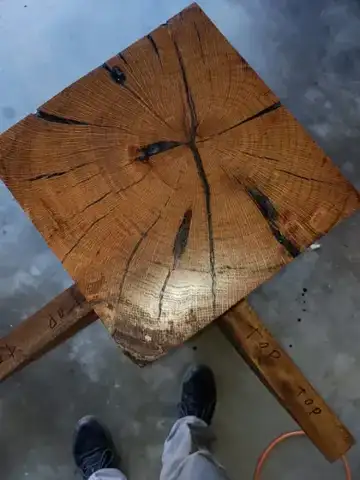 Square end-grain wood block with a dark crack, on angled legs
