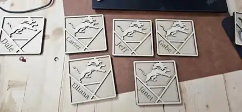 Laser-cut mountain-pattern wood coasters on a workbench