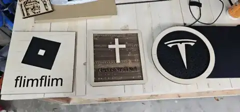 Engraved squares with logos and a cross on a workbench