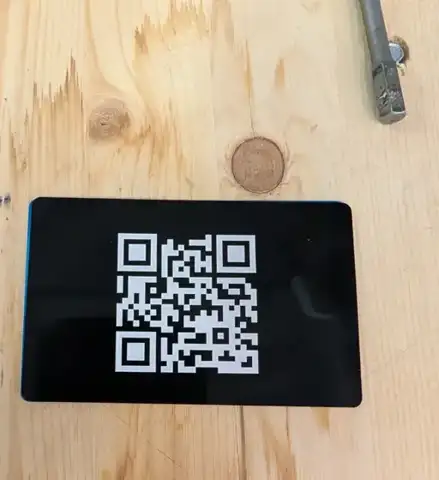 Black metal card engraved with a QR code