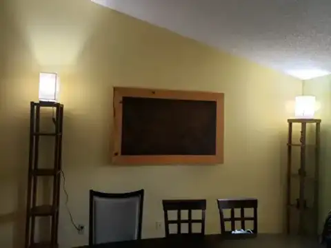 Framed dark wood wall piece between two tall lamps