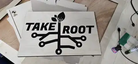 Take Root sign with a circuit-tree logo on the workbench