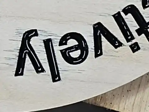 Close view of deep engraved black lettering on wood