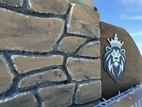 Stone-look wall with a lion head logo