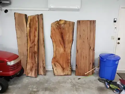 Live-edge slabs leaning against a garage wall