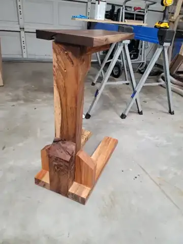 Wood stand with a dark top and a carved base