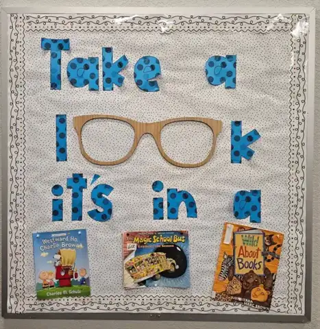 Bulletin board reading Take a look, it's in a book, with wood glasses